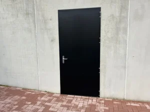 Utisteel zwarte branddeur in betonnen keerwand