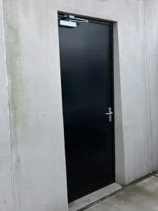 Zwarte brandwerende deuren met deurdranger buiten